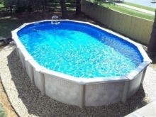 Oval pool with black commercial border landscaping with white marble chips