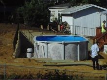 Completed retaining wall with black safety railing and 12' x 24' oval